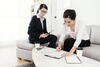 A woman in a suit reviewing a contract and plans with another woman on couch